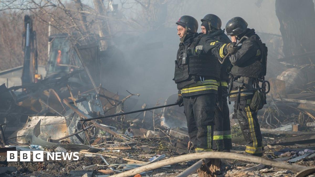 Firefighters work at the site of a missile strike in Kharkiv - a battered car can be seen next to a building that has also been hit