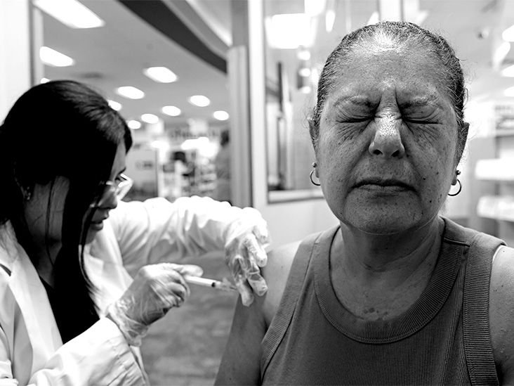 An odler adult woman gets vaccinated against shingles by a healthcare professional